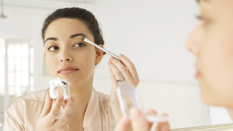 Woman applying makeup on her eyes