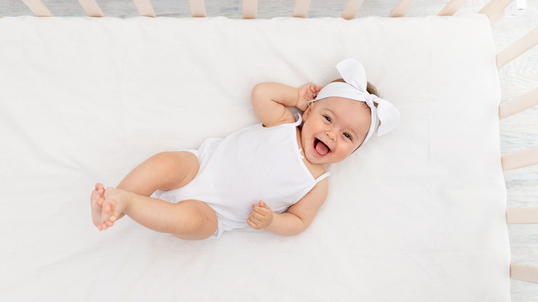 Smiling baby with bow in crib