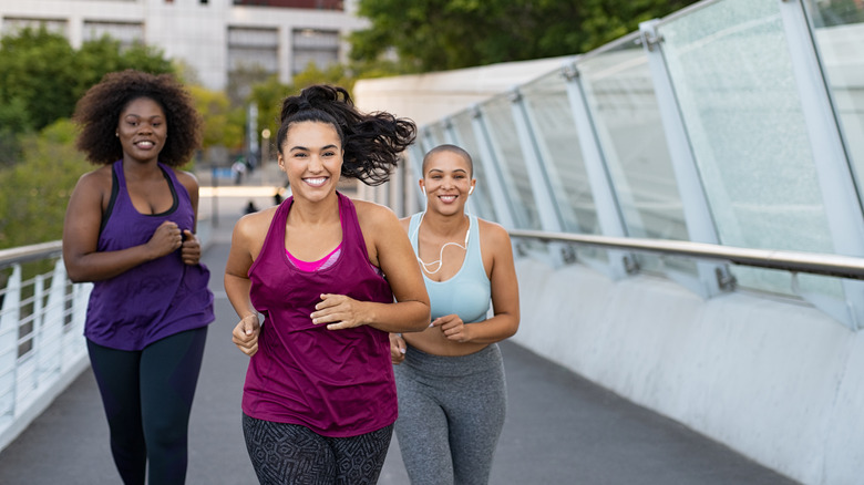 Three women running together on bridge