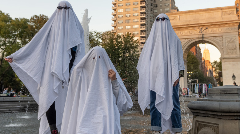 Three people dressed as ghosts Halloween