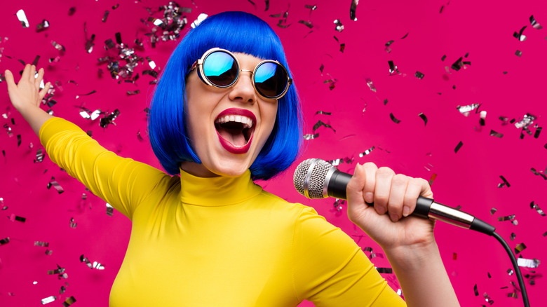 Woman with blue wig, sunglasses and microphone