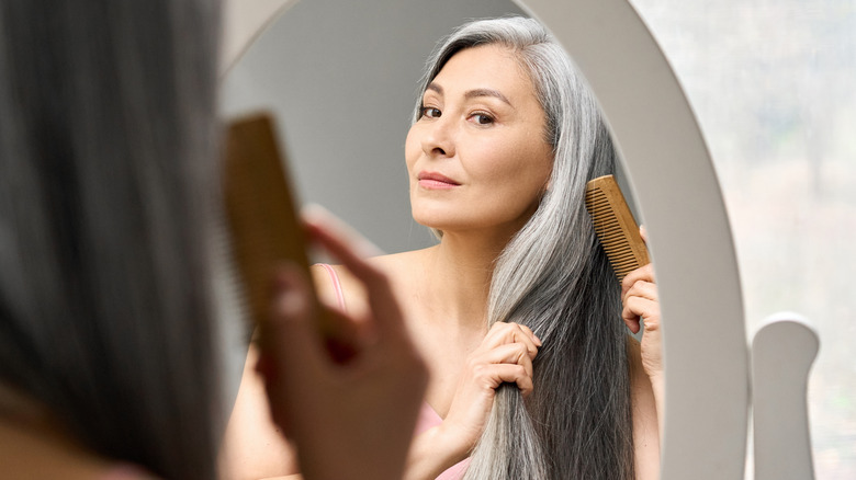 Woman styling her long hair in the mirror