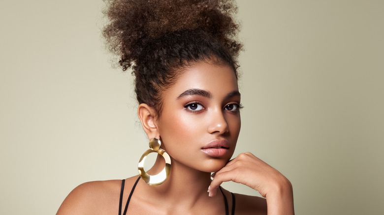 Woman posing & wearing large gold earrings