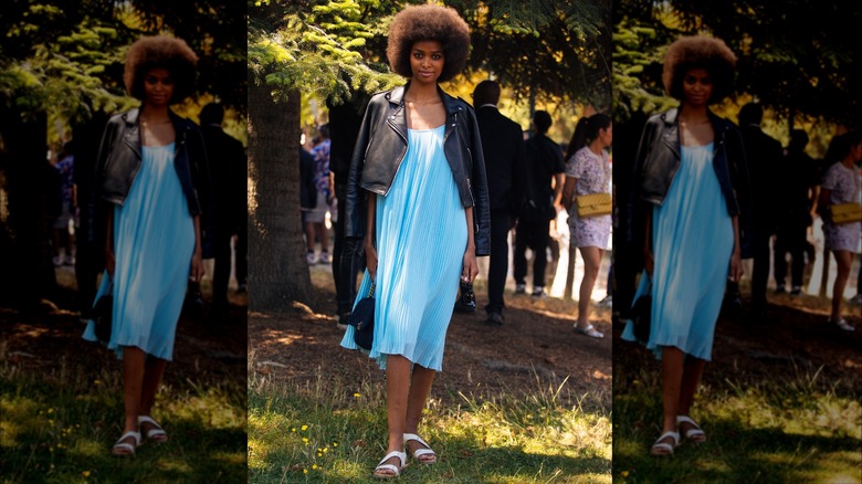 Woman wearing a black leather jacket over a blue sun dress