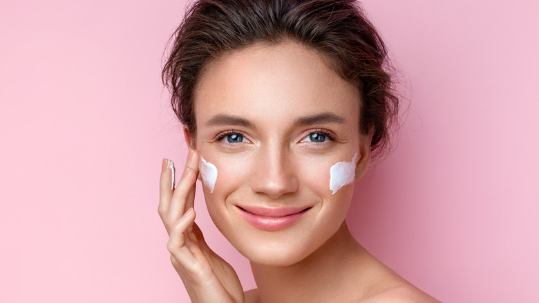 Woman putting lotion on her face