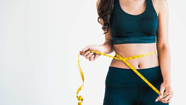 Woman measuring waist with tape