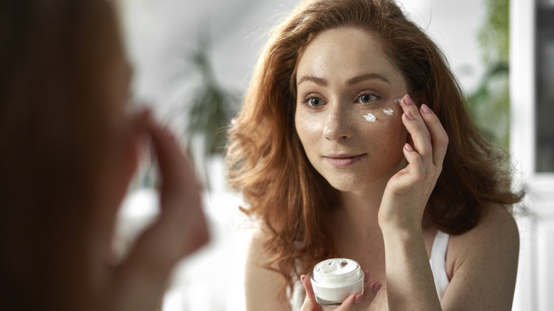 A woman applying moisturizer 