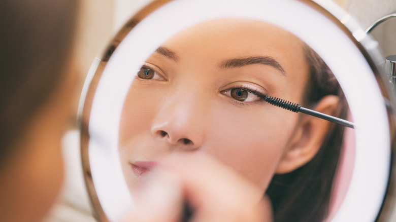 Woman applying mascara in the mirror