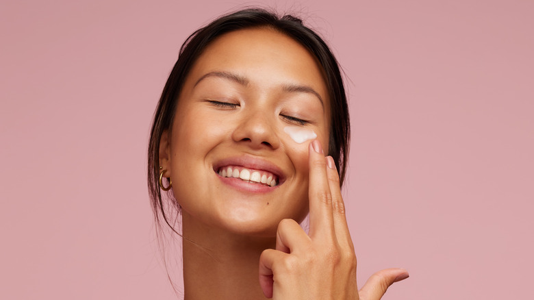 A woman applying cream on her face