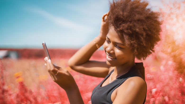 Black woman looking at hair in mirror