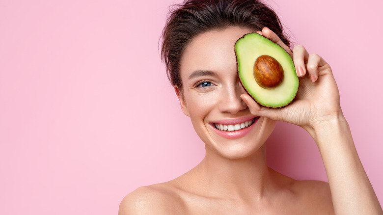 Smiling woman holds avocado