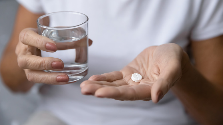 Woman holds water and pill