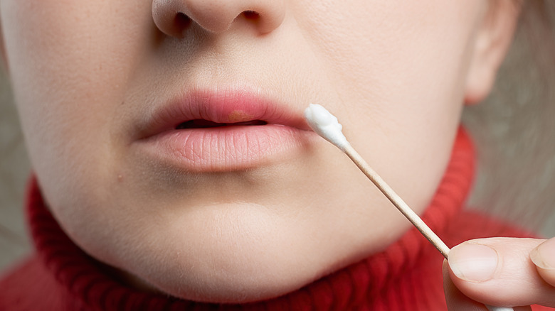 Woman applying cream to lips