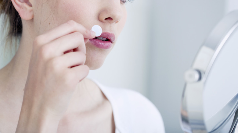 Woman applying cold sore patch