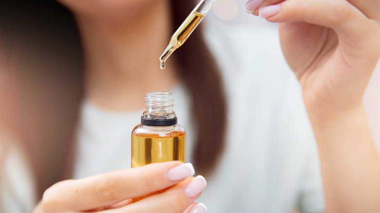 Woman holding oil dropper, bottle