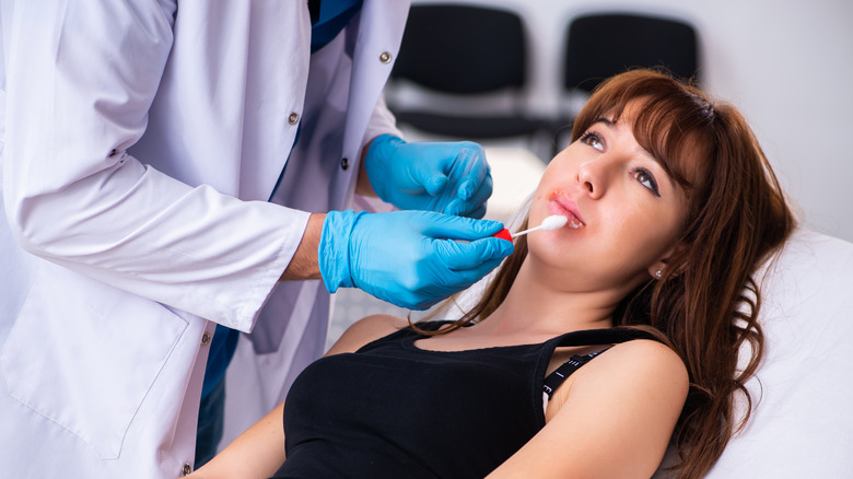 Doctor treating woman's cold sore