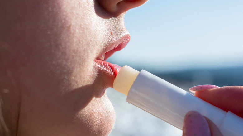 Woman applying lip balm outside