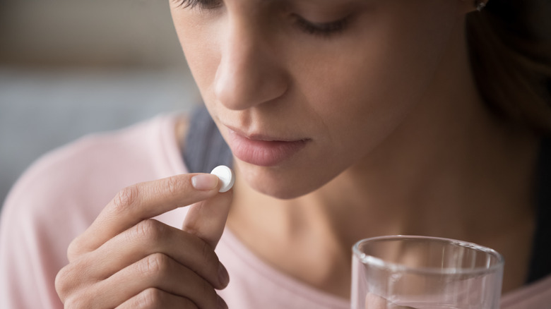 Young woman taking aspirin with a glass of water 