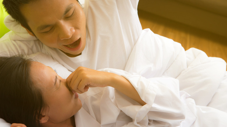 woman holding her nose at her partners morning breath 