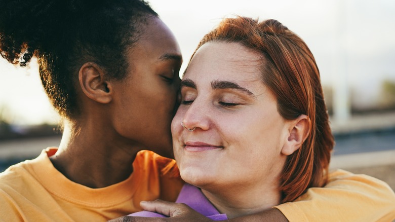 woman kissing smiling woman 