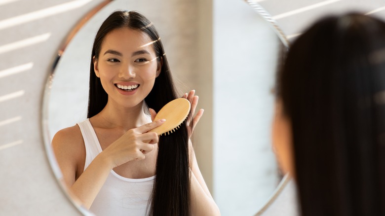 woman brushing hair in mirror