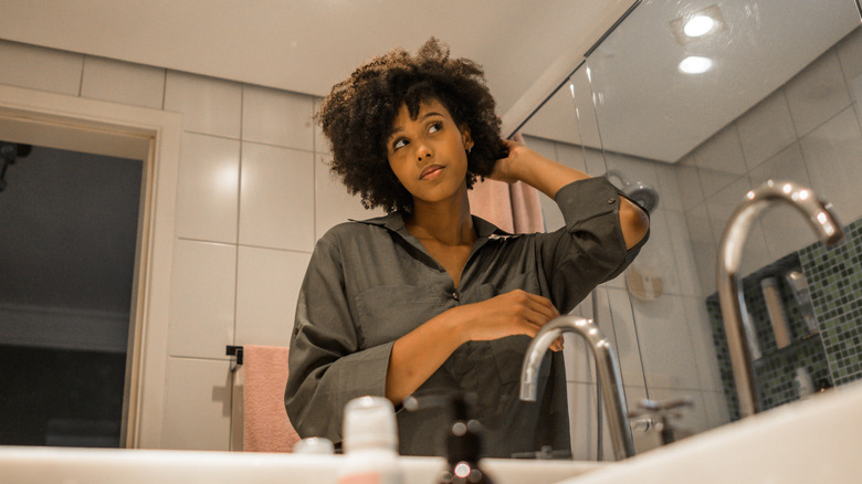 woman looking at hair in mirror