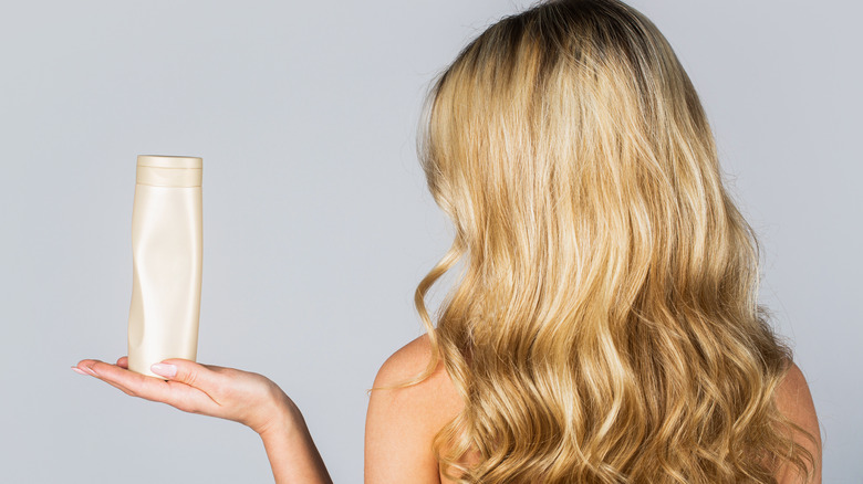 Blonde woman holding a shampoo bottle 