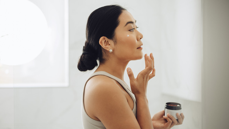 Side view woman applying skincare