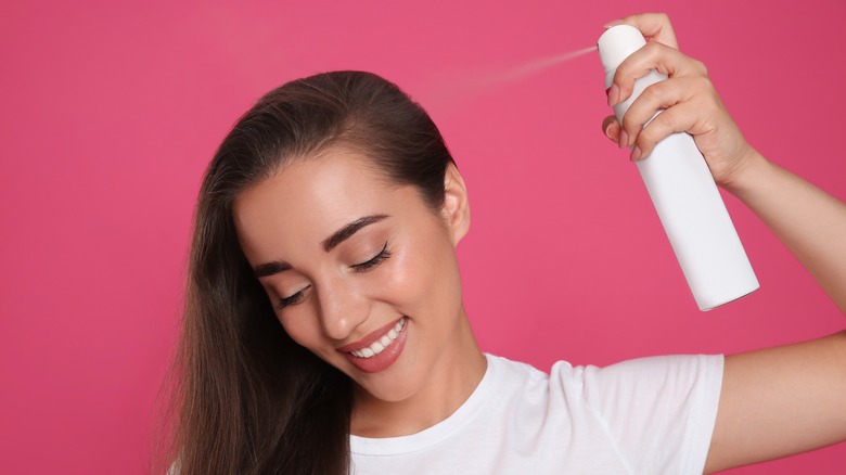 A woman applying dry shampoo