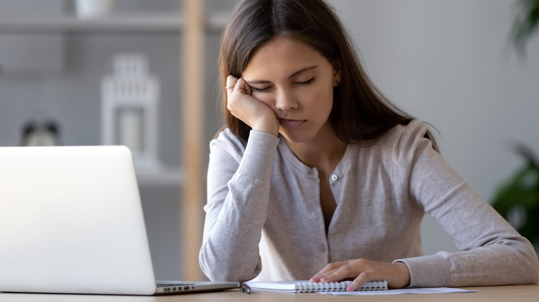 A woman resting in front of a computer. 