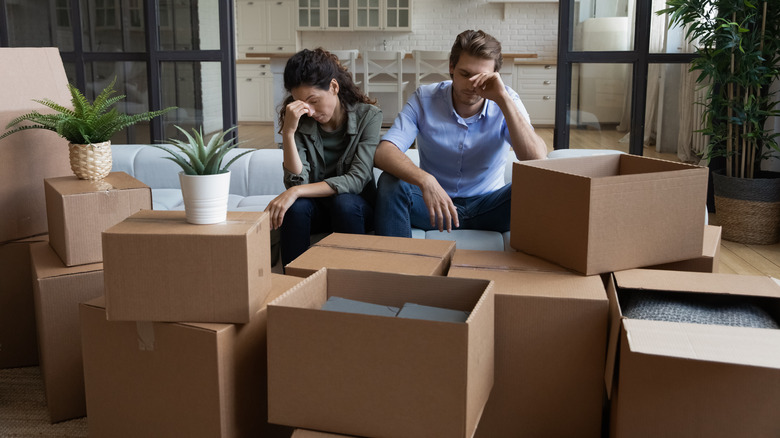 couple head hands around moving boxes