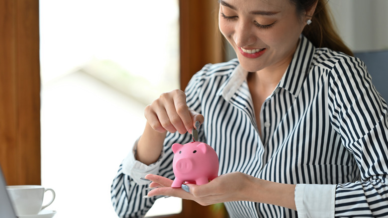 woman putting money in piggy bank