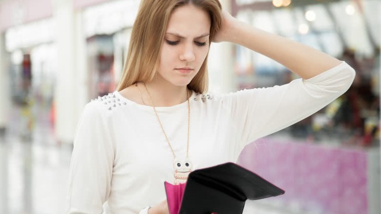 woman looking into empty wallet