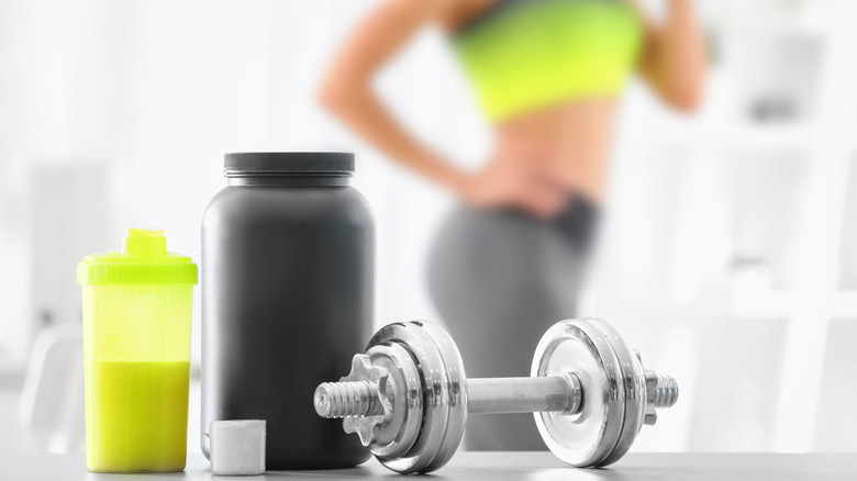 Protein powder, dumbbell, woman exercising