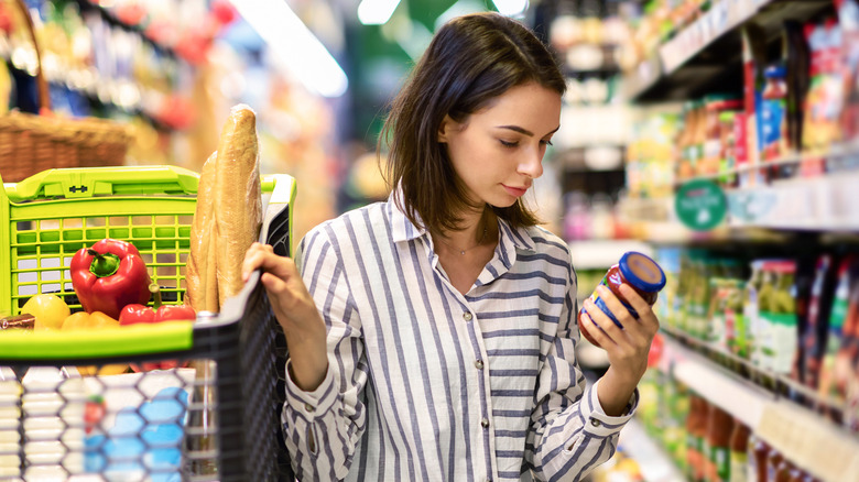 woman looking at jar in supermarket