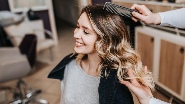 Woman sitting in a salon chair with curled and layered hair