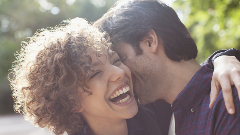 woman hugging boyfriend kissing her neck