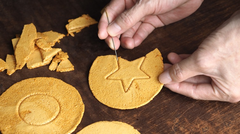 person cutting out dalgona candy shape