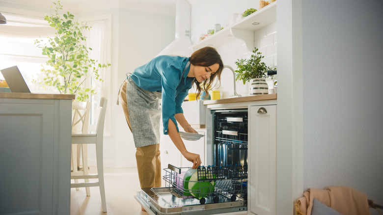 Woman bending over to put a dish in a dishwasher