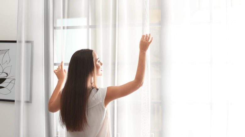 woman opening drapes