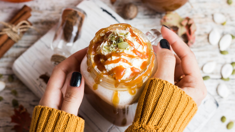 hands holding pumpkin spice latte