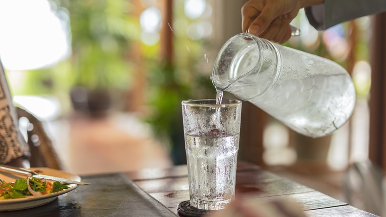 Woman pouring water from a pitcher at mealtime