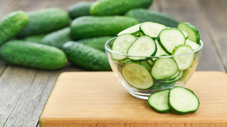 Cucumber slices in bowl on cutting board