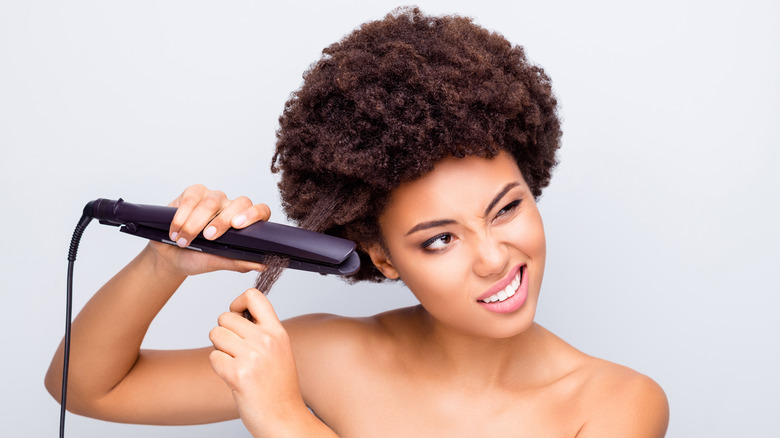 black woman straightening kinky hair