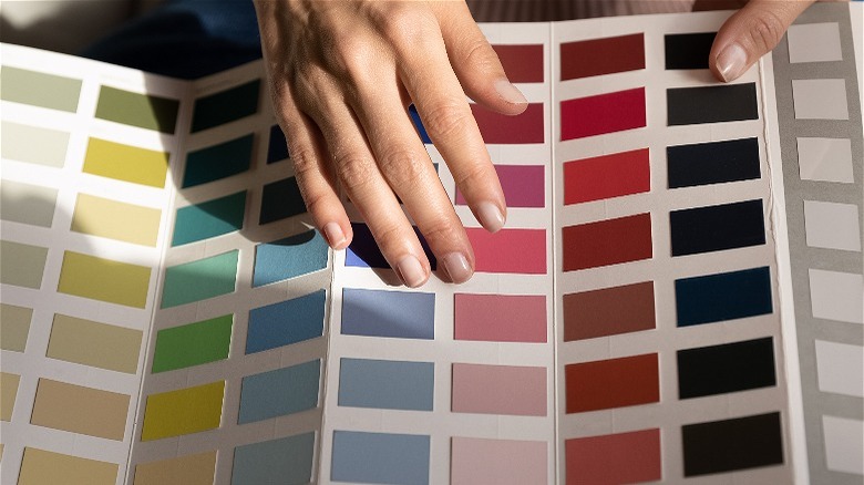 hands holding sheet of paint swatches