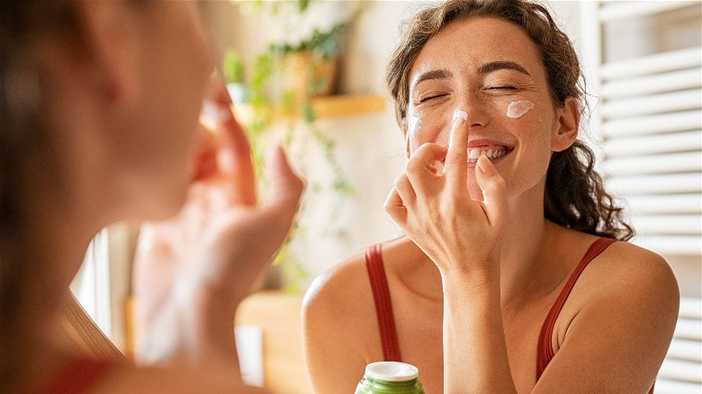 woman playfully puts moisturizer on nose