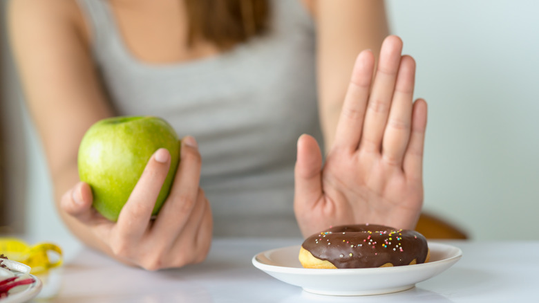 Woman choosing to eat an apple instead of a donut