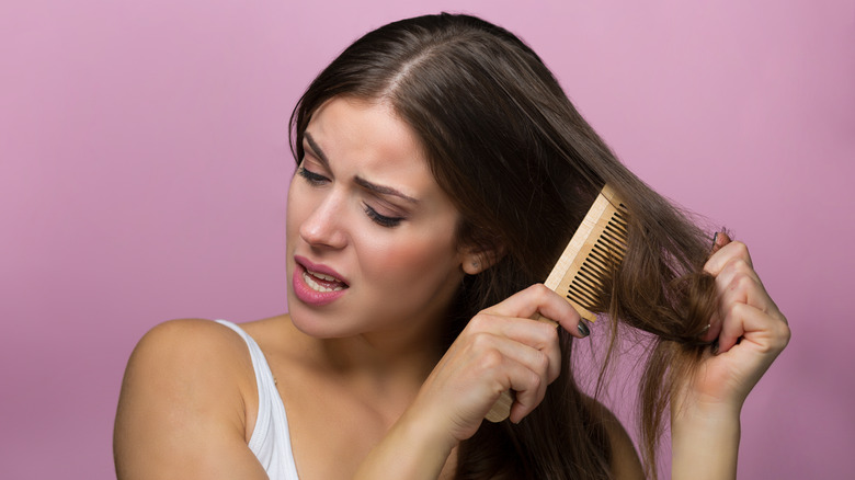 Woman trying to comb her tangled hair