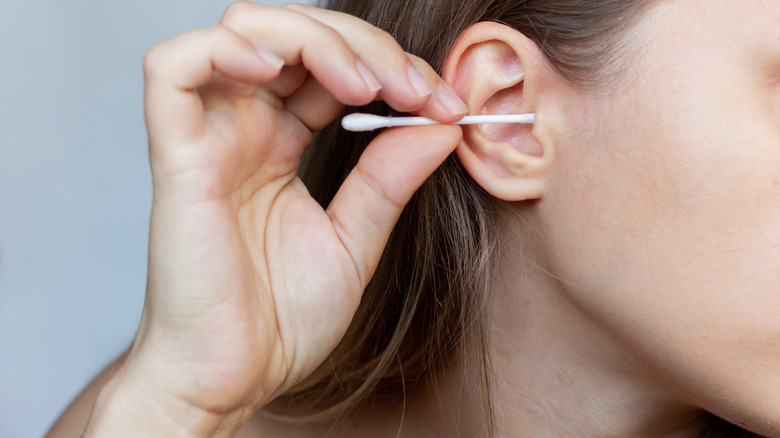 Woman cleans ear with cotton swab