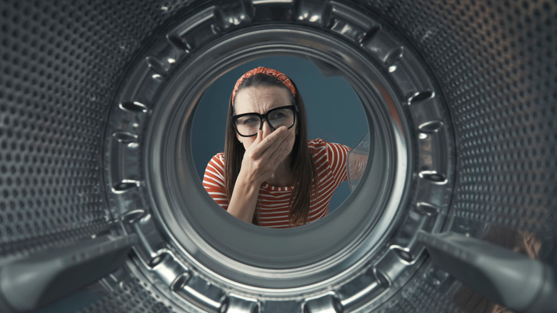 A woman looking into her washing machine. 